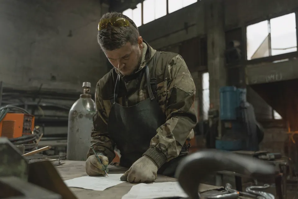 Symbolbild: Handwerker in Arbeitsjacke erledigt Papierkram in der Werkstatt